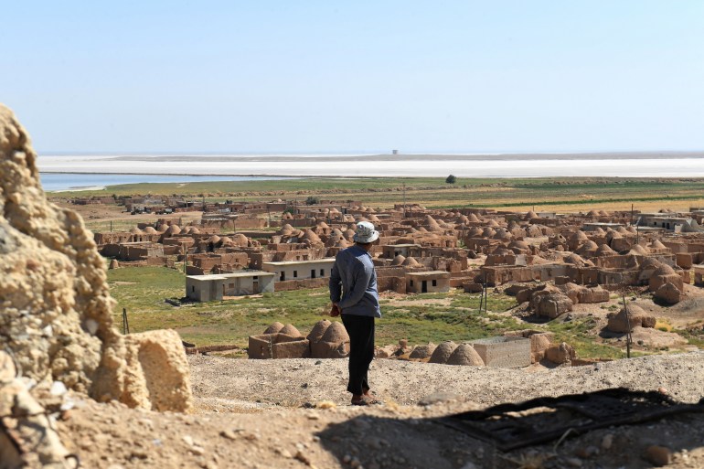 A man loosk at traditional mud-brick houses, known as 'beehive houses', in the village of Umm Amuda al-Kabira in Aleppo's eastern countryside, north of Damascus on August 11, 2023. - Traditional mud houses that residents of northern Syria have built for thousands of years risk disappearing, as 12 years of war have emptied villages and left the homes crumbling. The village in Aleppo province is among a handful of villages where residents long used to live in small domed houses made of mud bricks and brittle hay. (Photo by AFP)