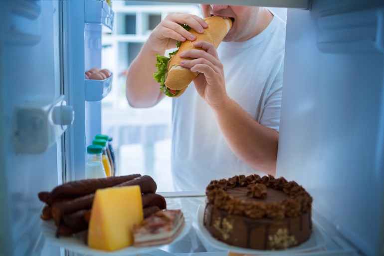 Overweight man on diet break diet with big sandwich roll; Shutterstock ID 567011821; purchase_order:Al Jazeera; job:; client:; other: