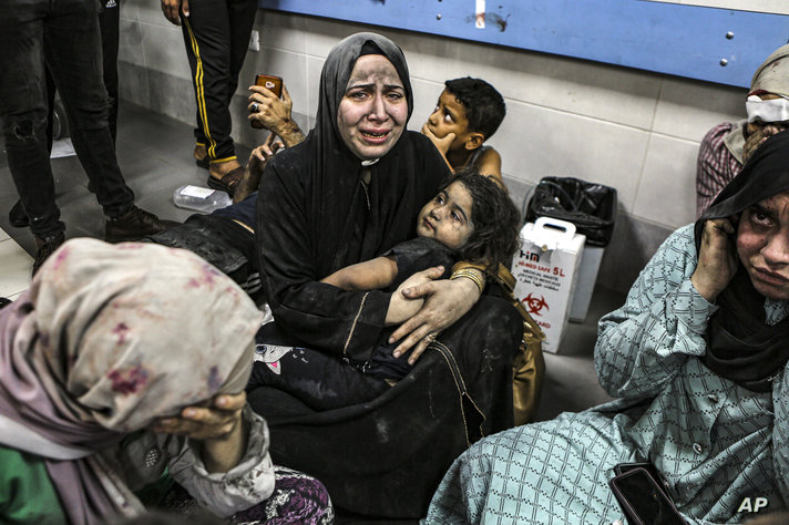 Wounded Palestinians sit in al-Shifa hospital in Gaza City, central Gaza Strip, after arriving from al-Ahli hospital following…