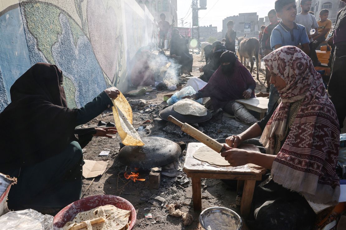 نساء فلسطينيات يصنعن الخبز التقليدي الفطير على نار مفتوحة في ملجأ للعائلات النازحة بشكل رئيسي من شمال قطاع غزة، في مدرسة تديرها الأمم المتحدة في رفح، في جنوب قطاع غزة في 27 أكتوبر 2023، وسط المعارك المستمرة بين إسرائيل وحركة حماس الفلسطينية.  (تصوير سعيد خطيب / وكالة الصحافة الفرنسية) (تصوير سعيد خطيب / وكالة الصحافة الفرنسية عبر غيتي إيماجز)