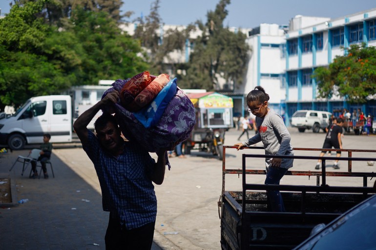 A Palestinian man who fled his home amid Israeli strikes, carries belongings to shelter in a United Nations-run school, in Gaza City October 8, 2023. REUTERS/Mohammed Salem