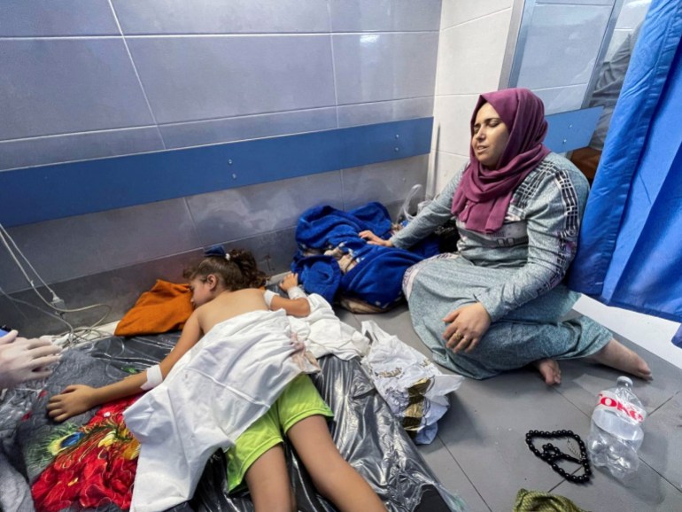 A Palestinian woman reacts next to a girl who was wounded in an Israeli strike, at Shifa hospital in Gaza City, October 15, 2023. REUTERS/Mohammed al-Masri