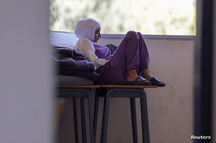 Children, who escaped  from the south Lebanese village of Dahaira near the Israeli border sits with their family lie down at a school where they take refuge in Tyre