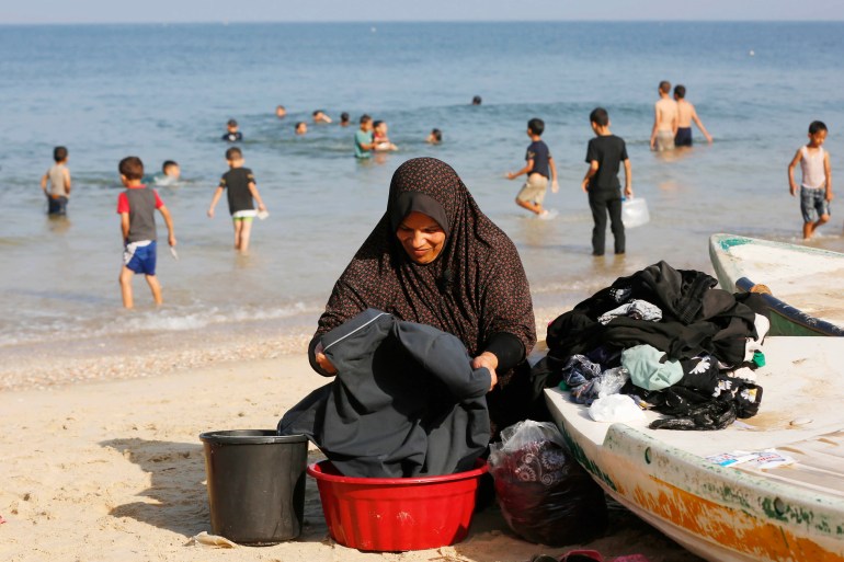 Andaleeb al-Zaq washes her family’s clothes using seawater, and says the school they are sheltering in has no running clean water [Ashraf Amra/Al Jazeera]