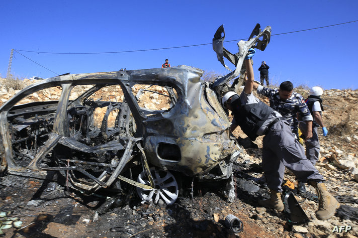 Rescuers from Hezbollah's Islamic Sanitary committee inspect the wreckage of a vehicle in which civilians were killed during an…