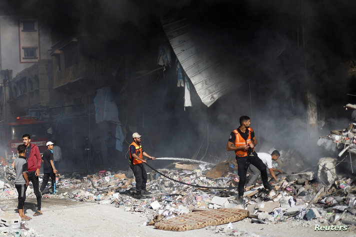 Palestinian firefighters work to put out a fire at the site of Israeli strikes on a residential building in Khan Younis