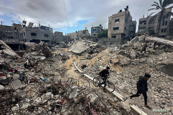 Palestinians inspect houses, destroyed in Israeli strikes during the conflict, at Khan Younis refugee camp