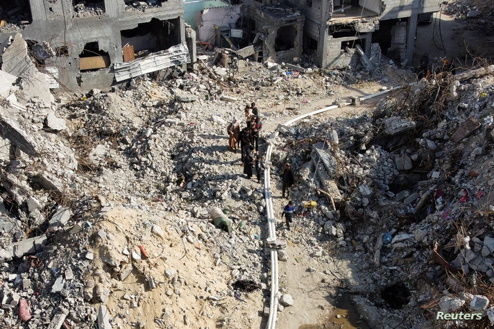 Palestinians inspect houses, destroyed in Israeli strikes during the conflict, at Khan Younis refugee camp