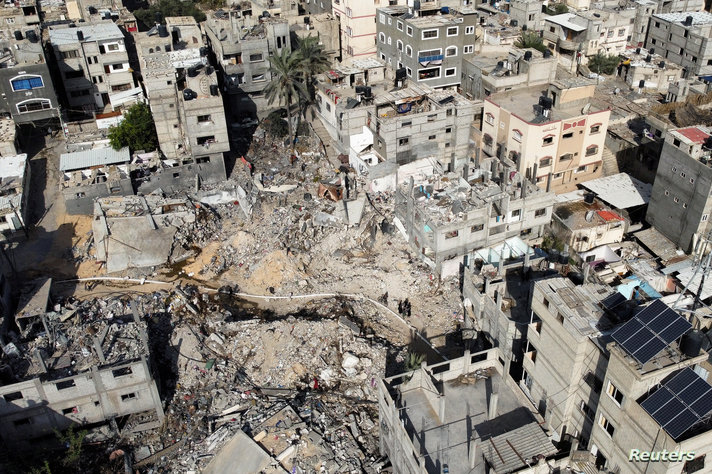 Palestinians inspect houses, destroyed in Israeli strikes during the conflict, at Khan Younis refugee camp