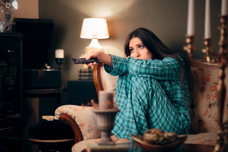 Girl Wearing Pajamas Watching TV in her Room. Funny woman binging television on programs and series