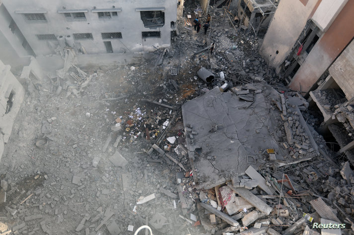 Palestinians inspect a house destroyed in an Israeli strike, in Khan Younis