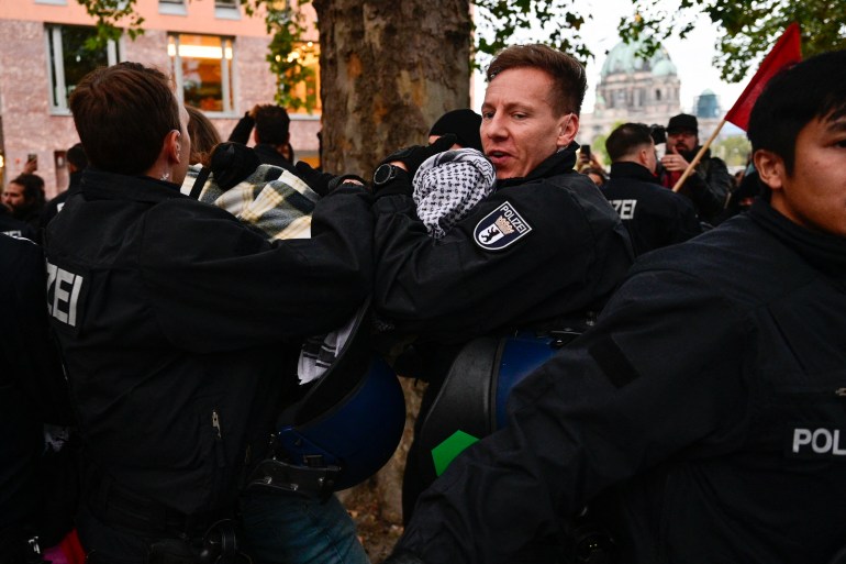 A demonstrator is dragged away by police during a demonstration against neo-colonialism and globalisation where protesters were shouting "free Palestine!" in front of the Foreign ministry with the Berlin Cathedral (Berliner Dom) in Berlin, Germany, on October 12, 2023. (Photo by John MACDOUGALL / AFP)