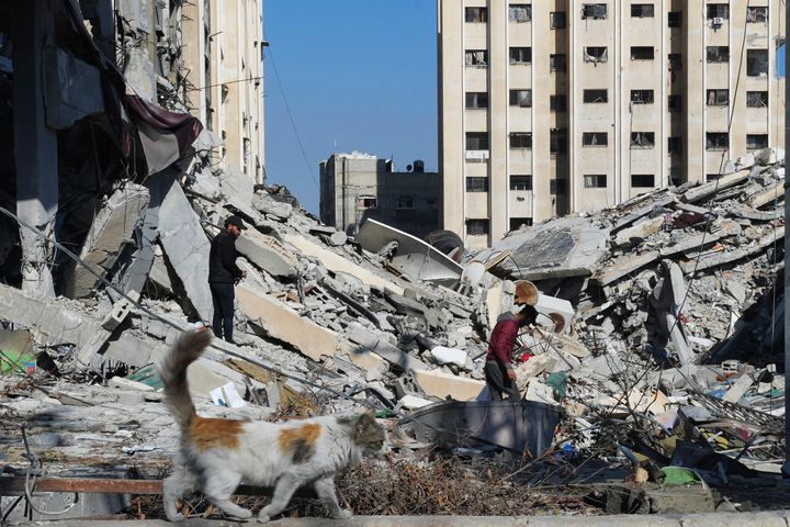 فلسطينيون يسيرون وسط الدمار الناجم عن القصف الإسرائيلي في مخيم النصيرات للاجئين في قطاع غزة، الجمعة، 19 يناير، 2024. (AP Photo/Adel Hana)