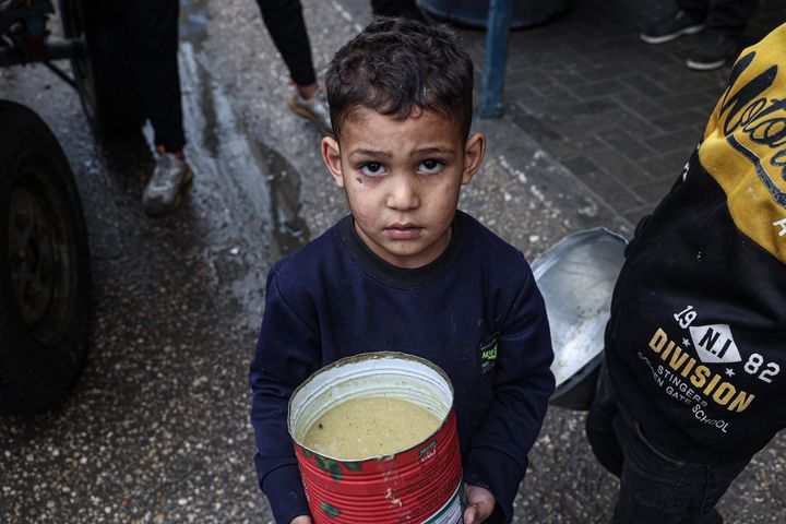 طفل فلسطيني نازح يحمل حصة من حساء العدس الأحمر، وزعها متطوعون في رفح بجنوب قطاع غزة في 18 فبراير، 2024. بعد أكثر من أربعة أشهر من الحرب التي سوت مساحات شاسعة من القطاع بالأرض، يقترب سكان غزة من المجاعة بحسب برنامج الغذاء العالمي التابع للأمم المتحدة.