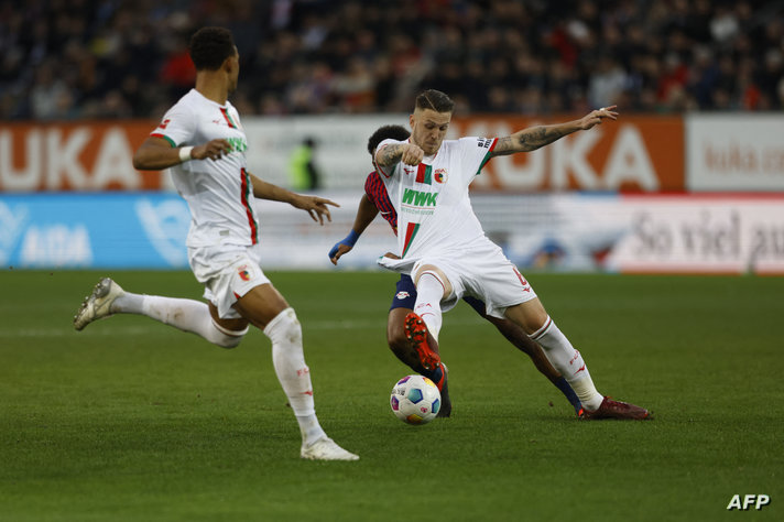 Leipzig's Belgian forward #17 Lois Openda (hidden) and Augsburg's Dutch defender #06 Jeffrey Gouweleeuw (R) vie for the ball…