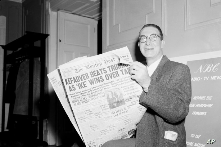 Sen. Estes Kefauver (D-Tenn) flashes a victory smile as he reads the newspaper, in Concord, N.H., Mar. 12, 1952, telling of his…