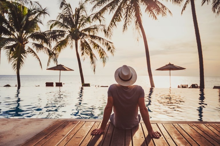 tourist in luxury beach hotel near luxurious swimming pool at sunset, getaway, tropical exotic holidays vacation, tourism and travel