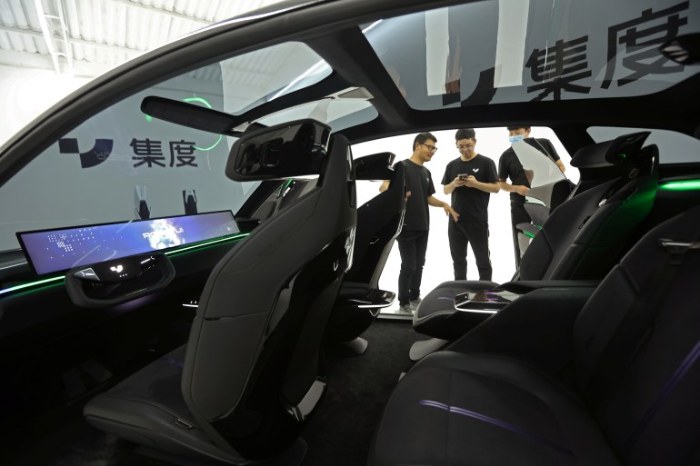 Staff members stand near ROBO-01, a "robot" concept car by Baidu's electric vehicle (EV) arm Jidu Auto, which is displayed during a media preview before its debut, in Beijing, China June 8, 2022. REUTERS/Tingshu Wang