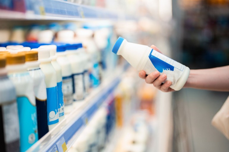 Close up shot of woman holding a bottle of organic fresh milk in supermarket