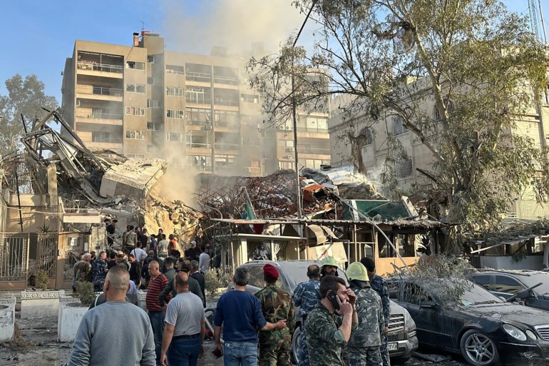 Emergency and security personnel gather at the site of strikes which hit a building adjacent to the Iranian embassy in Syria's capital Damascus, on April 1, 2024. - Israeli strikes hit Syria's capital on April 1, state media reported, as a war monitor said six people were killed in a building adjacent to the Iranian embassy. (Photo by Maher AL MOUNES / AFP)