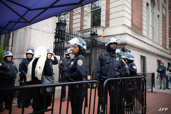 NYPD Officers stand guard by one of the gates of Columbia University in New York City on April 18, 2024. - Officers cleared out…