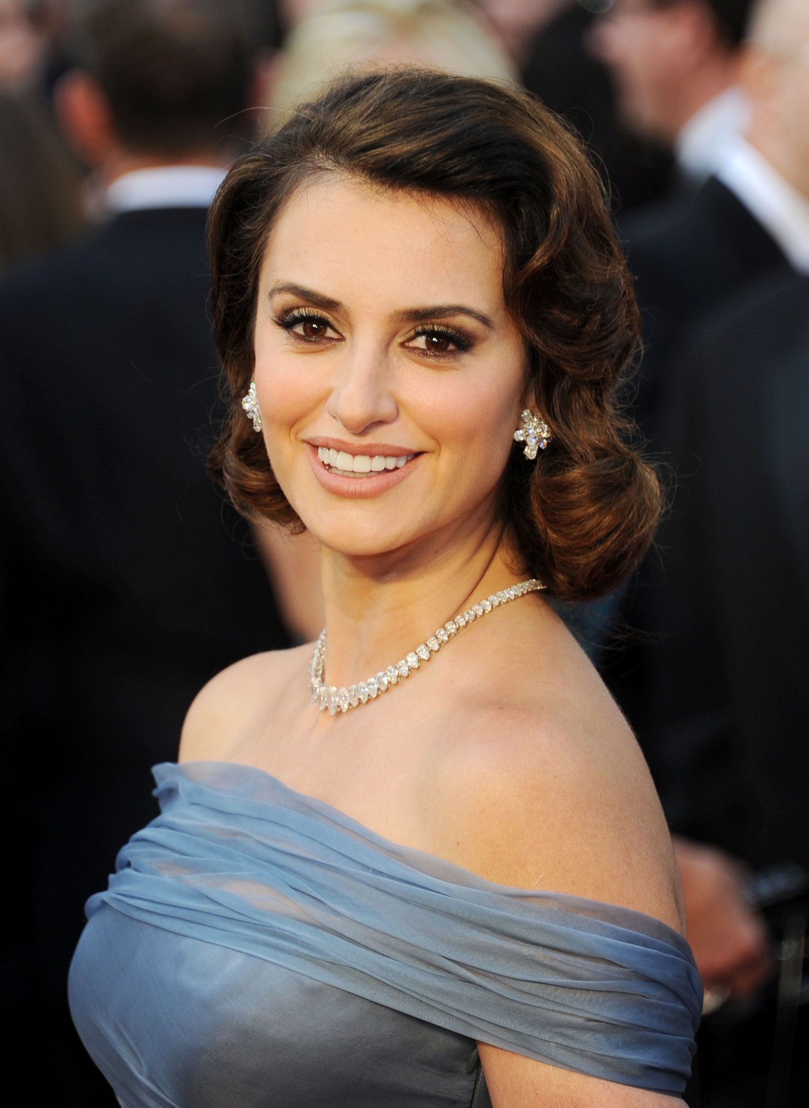 ربما تحتوي الصورة على Penlope Cruz رأس شخص وجه ابتسامة سعيدة إكسسوارات مجوهرات قلادة ملابس وفستان