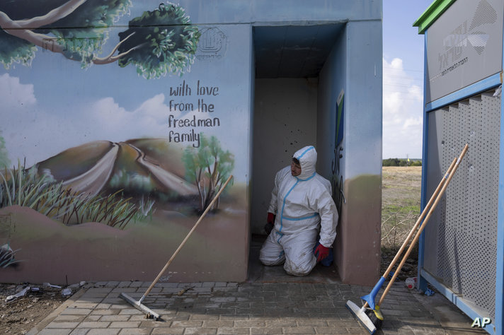 FILE - Volunteers from the ZAKA rescue service remove blood stains from a public bomb shelter on a road near the Israeli-Gaza…