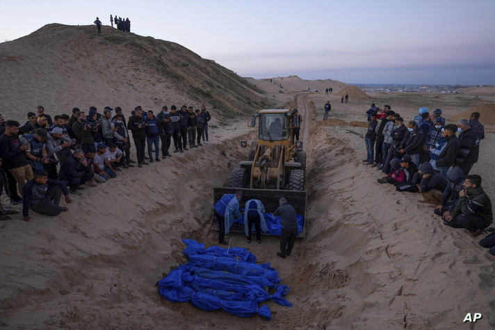 FILE - A bulldozer unloads the bodies of Palestinians killed in Israeli strikes and turned over by the Israeli military during…