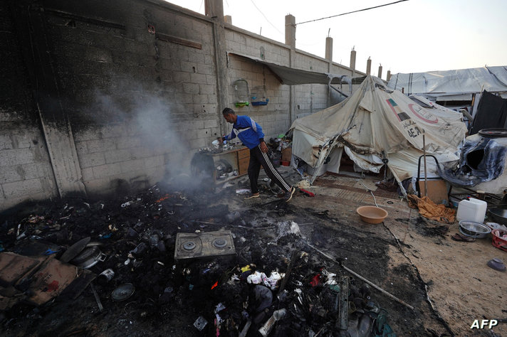 Smoke rises from the ashes in a tented area, the day after a strike on the al-Mawasi area, northwest of the Palestinian city of…