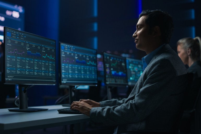 Confident Male Data Scientist Works on Personal Computer in Big Infrastructure Control Room. Stock Market Male Specialist Uses Computer Showing Charts, Information. Monitoring Room Team; Shutterstock ID 1976669126; purchase_order: aljazeera ; job: ; client: ; other: