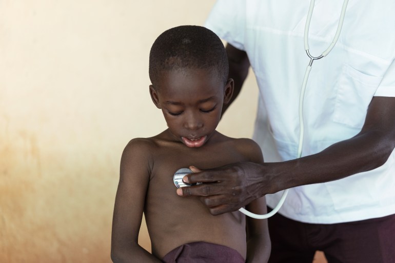 Black African toddler looking with interest on his chest during lung examination with a stethoscope