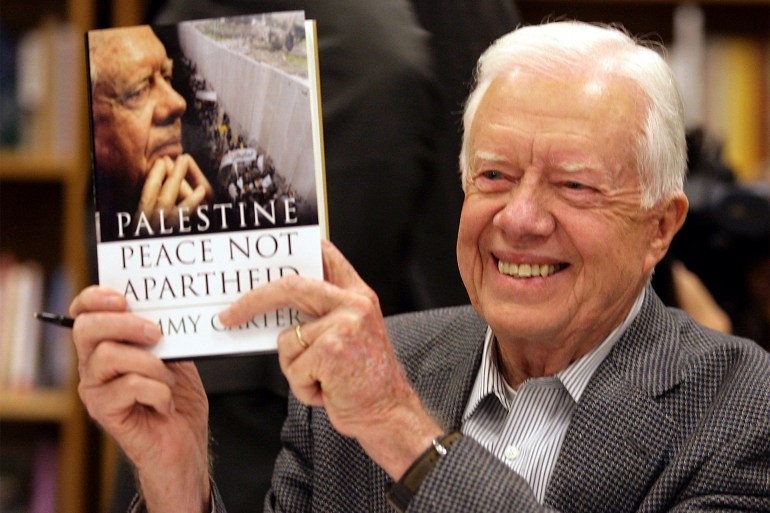 FILE - Former President Jimmy Carter holds a copy of his book, "Palestine: Peace, Not Apartheid," at a book signing in Tempe, Ariz., Dec. 12, 2006. (AP Photo/Paul Connors, File)