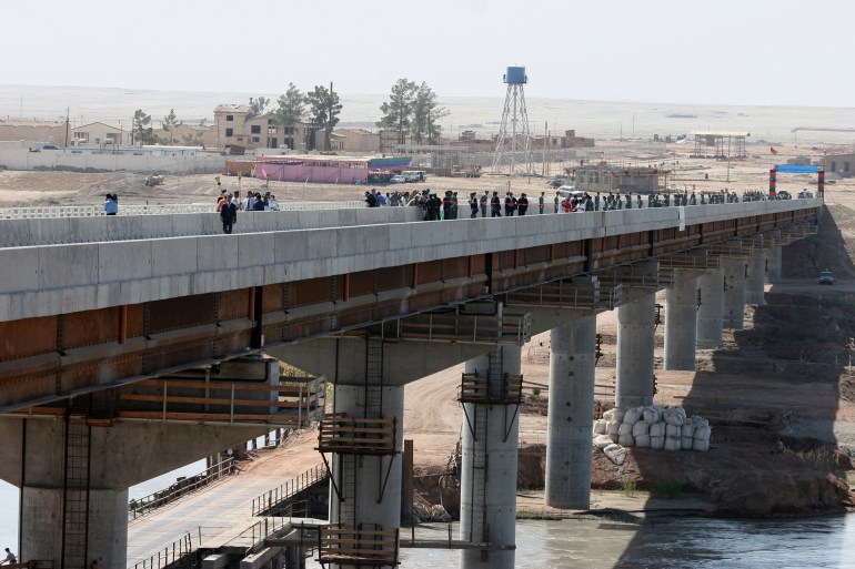 People walk along a bridge during an opening ceremony in Nizhny Panj at the Afghan-Tajik border, 26 August 2007. A road bridge linking Tajikistan and Afghanistan paid for by the United States was officially opened on Sunday at a ceremony attended by the presidents of the two Central Asian countries. AFP PHOTO / STR (Photo by AFP)