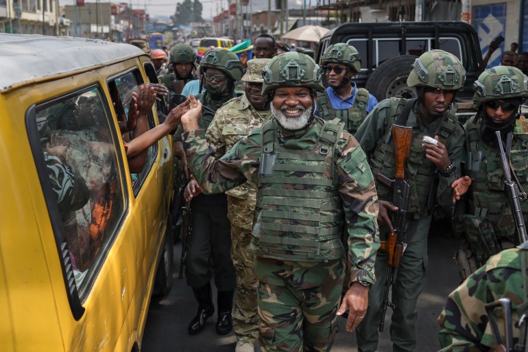 Leader of Alliance Fleuve Congo (AFC), Corneille Nangaa (C), a political-military movement of rebel groups including the M23 group, shakes hands with passengers in a public service taxi as he is received with jubilation by residents during a clean up exercise of the city of Goma on February 1, 2025. The Rwandan-backed M23 group was pushing south in mineral-rich eastern DR Congo as the United Nations warned the escalating conflict had killed at least 700 people in less than a week. The M23 took vital eastern trade hub Goma after intense fighting this week and has vowed to march all the way to the Democratic Republic of Congo capital. (Photo by Tony KARUMBA / AFP)