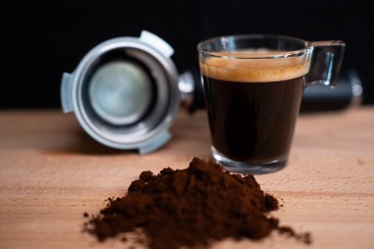 A glass of espresso coffee, a portafilter, and some espresso coffee blend are sitting on a wooden surface. (Photo by Nikos Pekiaridis/NurPhoto via Getty Images)