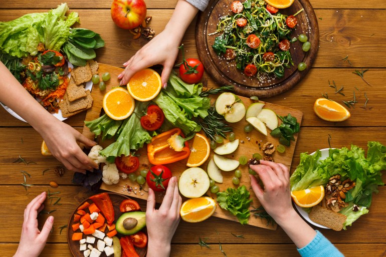 Healthy food dinner table. Women at home together, eating fruits and vegetables, top view, flat lay, crop