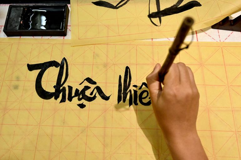 This photo taken on May 15, 2025 shows Hoang Thi Thanh Huyen learning calligraphy at the home of calligrapher Nguyen Thanh Tung in Hanoi. At a calligraphy class in Hanoi, Hoang Thi Thanh Huyen slides her brush across the page to form the letters and tonal marks of Vietnam's unique modern script, in part a legacy of French colonial rule. (Photo by Nhac NGUYEN / AFP) / TO GO WITH VIETNAM-FRANCE-ALPHABET-DIPLOMACY-MACRON, FOCUS