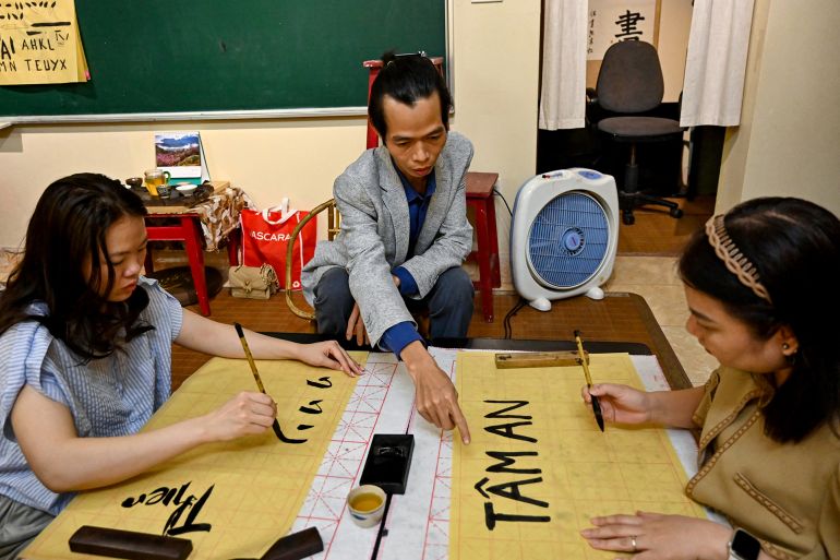 This photo taken on May 15, 2025 shows calligrapher Nguyen Thanh Tung (C) teaching calligraphy to students at his home in Hanoi. At a calligraphy class in Hanoi, Hoang Thi Thanh Huyen slides her brush across the page to form the letters and tonal marks of Vietnam's unique modern script, in part a legacy of French colonial rule. (Photo by Nhac NGUYEN / AFP) / TO GO WITH VIETNAM-FRANCE-ALPHABET-DIPLOMACY-MACRON, FOCUS